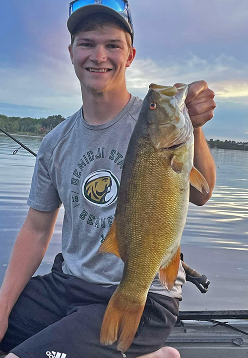 image of young man holding huge smallmouith bass caught in the Ely Minnesota region