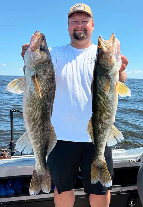 image of a fisherman holding a pair of walleyes caught on Lake of the Woods