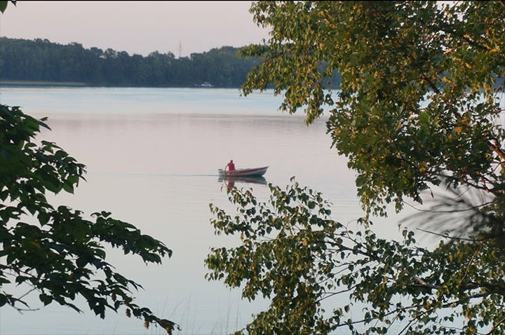 image of fisherman in a small boat on the lake