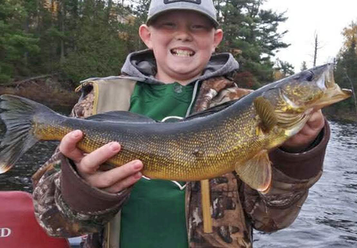 image of young boy holding large walleye caught near the Ely MN area